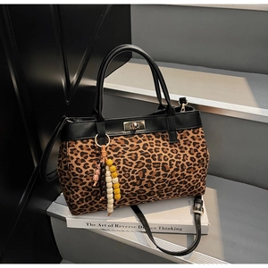 Dettaglio borsa leopardata con chiusura dorata e ciondolo di perline sulle scale grigie
