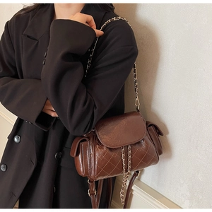 Détail du sac bandoulière marron foncé matelassé avec chaîne en métal vintage et cuir