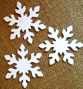 Laser cut white snowflake paper cards on burlap background for festive holiday decoration