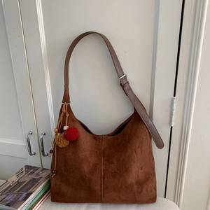 Détail du sac hobo marron mat avec breloques décoratives en peluche et bandoulière réglable