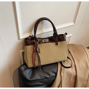 Detail view of khaki suede handbag with contrasting dark brown leather handle and metal lock