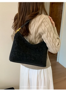 Detailed view of the black retro crescent shoulder bag with golden hardware on a model