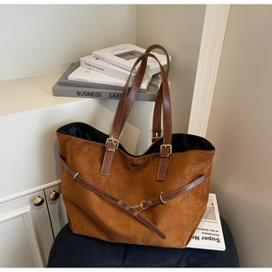 Close-up of brown suede tote bag featuring deep brown leather straps and gold metal buckles