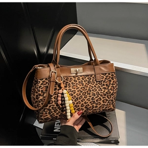 Dettaglio della borsa tote leopardata con finiture in pelle marrone e chiusura dorata