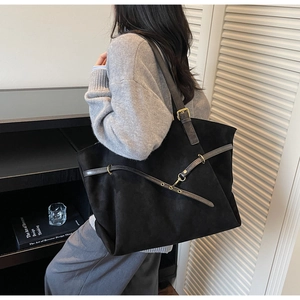 Detail of black matte tote bag with slim leather straps and gold metallic hardware accents
