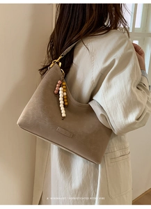 Detail of retro leather hobo bag with vintage texture and stylish beaded pendant