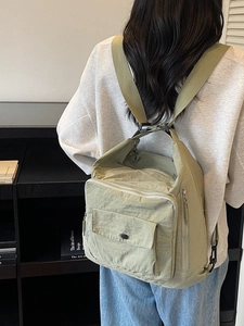 Light green nylon backpack with multiple pockets and adjustable straps in a lifestyle setting