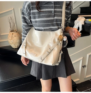 Close-up of the beige PU leather crossbody bag with decorative buckles and metal logo plaque
