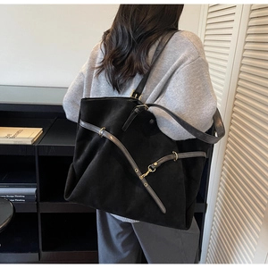 Detail of vintage matte black tote bag showing gold buckles and decorative straps on model