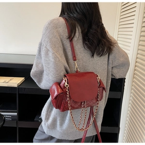 Gros plan d'un sac bandoulière matelassé rouge foncé avec chaîne dorée sur mannequin