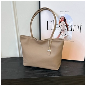 Close-up of light brown lychee grain leather tote bag with elegant gold chain accessory