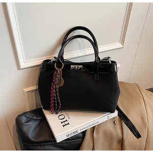 Detail of black matte handbag with glossy trim, silver twist lock and sports charms