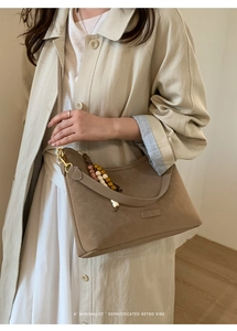 Detailed view of khaki retro bucket bag with colorful wooden beads on a stylish model