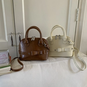 Close-up of mini shell bags with bow details in brown and cream vintage leather