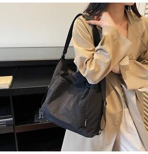 Close-up of black nylon tote bag with woven zipper pull and adjustable strap detail