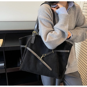 Macro view of black suede tote bag featuring premium leather straps and gold buckle details