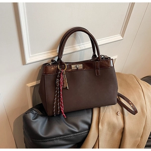 Detail of vintage brown frosted leather handbag with silver twist lock and woven tassel