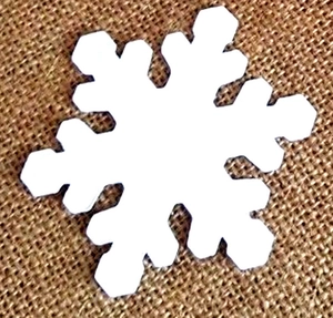 Macro shot of laser-cut white snowflake card on brown linen background for wedding decor