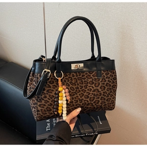 Dettaglio borsa scamosciata leopardata con chiusura a rotazione in metallo e nappa in legno