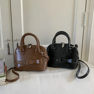 Detailed view of mini shell bags in brown and black leather with ribbon bow accents