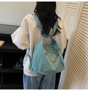 Detail of blue-green nylon backpack showing waterproof wrinkled texture and side zipper
