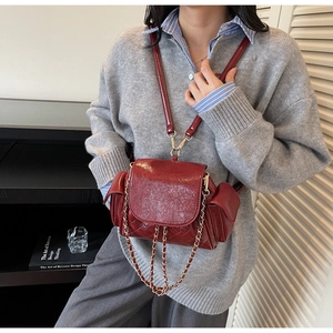 Détail d'un mini sac à dos en cuir matelassé bordeaux avec chaîne dorée sur mannequin