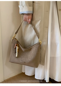 Detail of khaki leather bucket bag with bohemian bead charm and vintage matte texture