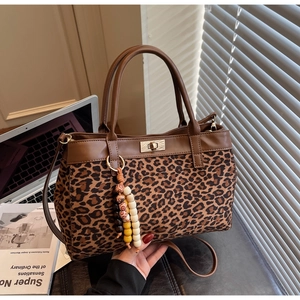 Dettaglio borsa tote leopardata con chiusura girevole in metallo dorato e ciondolo