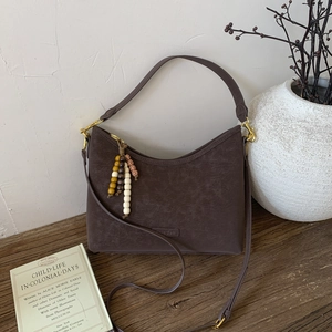 Detail of dark brown vintage shoulder bag with bead tassel and matte leather texture