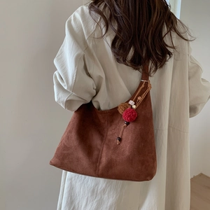 Gros plan sur la texture du sac hobo en daim marron avec pendentif à pompons