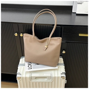 Detail of light brown tote bag with lychee texture and elegant gold chain ornament