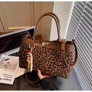 Dettaglio della borsa tote scamosciata leopardata con finiture in ecopelle marrone e nappe
