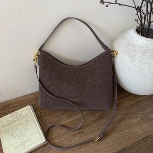 Close-up of vintage brown suede shoulder bag with gold hardware on rustic wooden table