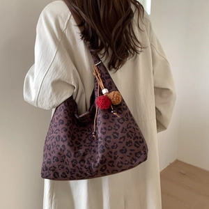 Détail du sac en toile imprimé léopard avec pendentifs décoratifs en peluche