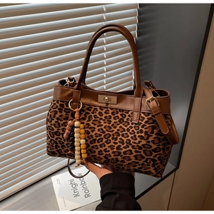 Dettaglio della borsa leopardata con manici in pelle marrone e ciondolo di perline