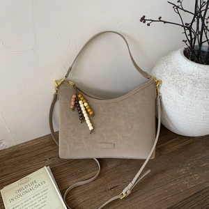 Detail of light brown suede shoulder bag with colorful wooden beads and golden hardware