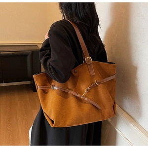 Detail of vintage brown suede tote bag with leather straps and gold metal hardware buckles