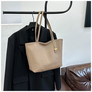 Detail of beige pebbled leather tote bag with gold chain charm and large interior