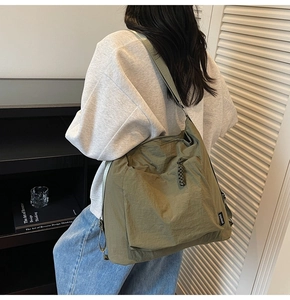 Detail of army green nylon shoulder bag showing a side view and its large capacity