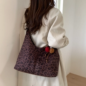 Vue détaillée d'un grand sac hobo léopard avec un pompon en peluche porté par un mannequin
