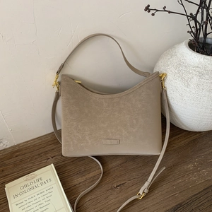 Close-up of beige retro hobo bag with gold hardware and embossed logo on vintage background