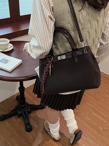 Retro brown leather tote bag with silver twist lock and plaid charm shown in a cafe
