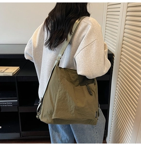 Close-up of olive green nylon tote bag with black logo and knot zipper detail