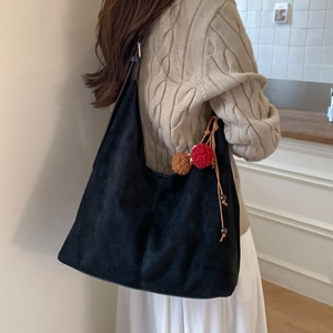 Vue détaillée du sac à bandoulière en daim noir avec pompon marron sur un modèle