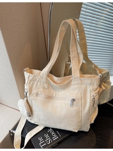 Minimalist off-white canvas tote bag with adjustable shoulder strap and small round pouch