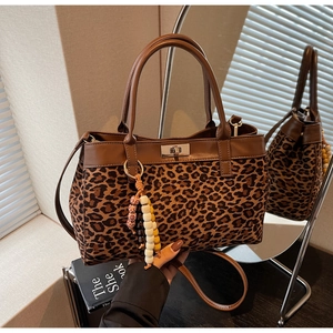 Dettaglio della borsa leopardata con manici in pelle marrone e chiusura a girello in metallo