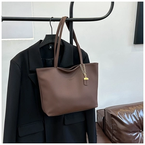 Detail shot of brown lychee grain leather tote bag with elegant gold metal chain