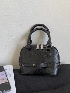 Glossy black shell-shaped handbag with pleated texture and stylish bow detail