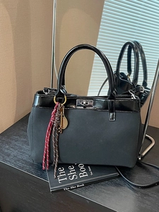 Black high-end mixed texture handbag with metallic lock and braided charm detail