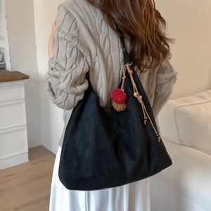 Détail du sac dumpling noir mat avec pompon décoratif et cordon de serrage en cuir